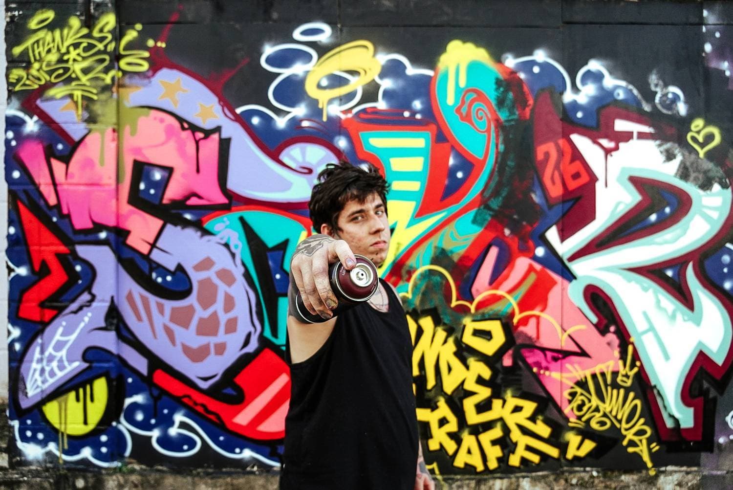Riverón pointing a spray can at the camera in front of an UNDERGRAFF graffiti wall