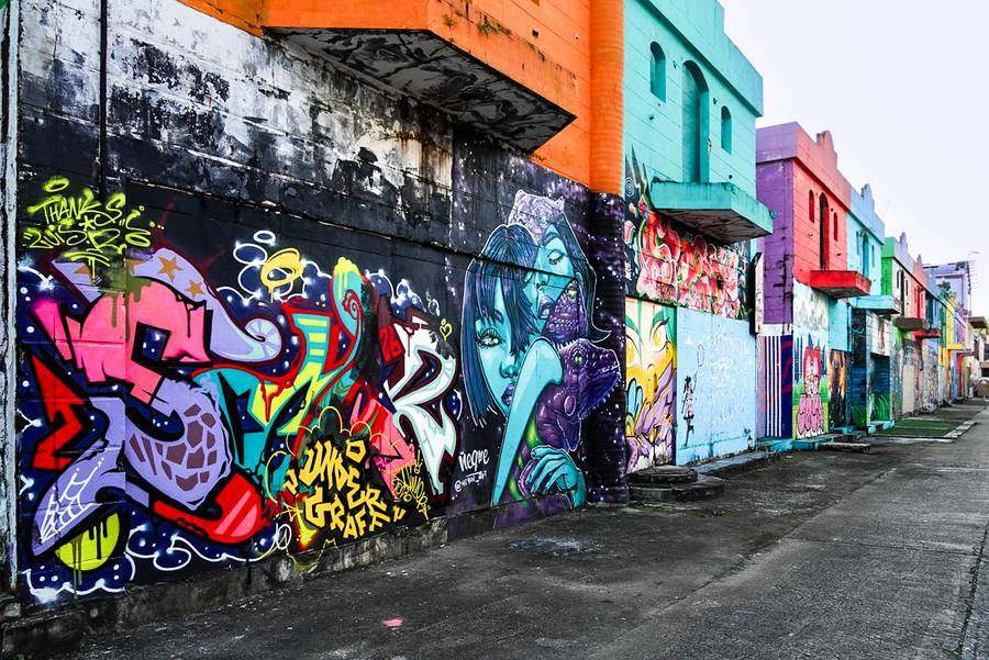 Alley lined with colorful murals, with UNDERGRAFF painted in yellow letters